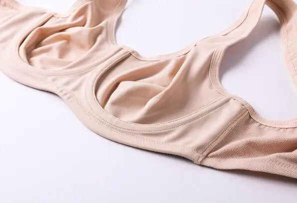 A close-up of a beige seamless bra with molded cups, laid flat on a white background.