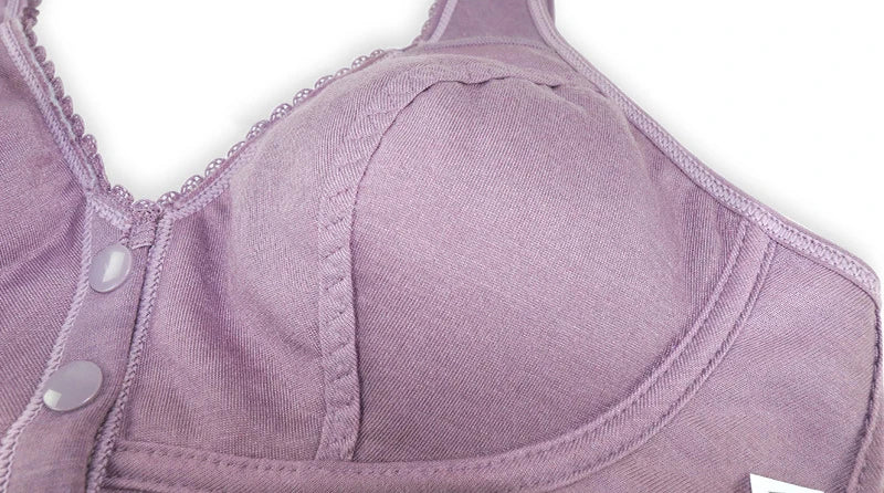 Close-up of a lavender-colored bra with a textured fabric, decorative lace trim along the neckline, and a snap button closure on the left side, set against a plain white background.