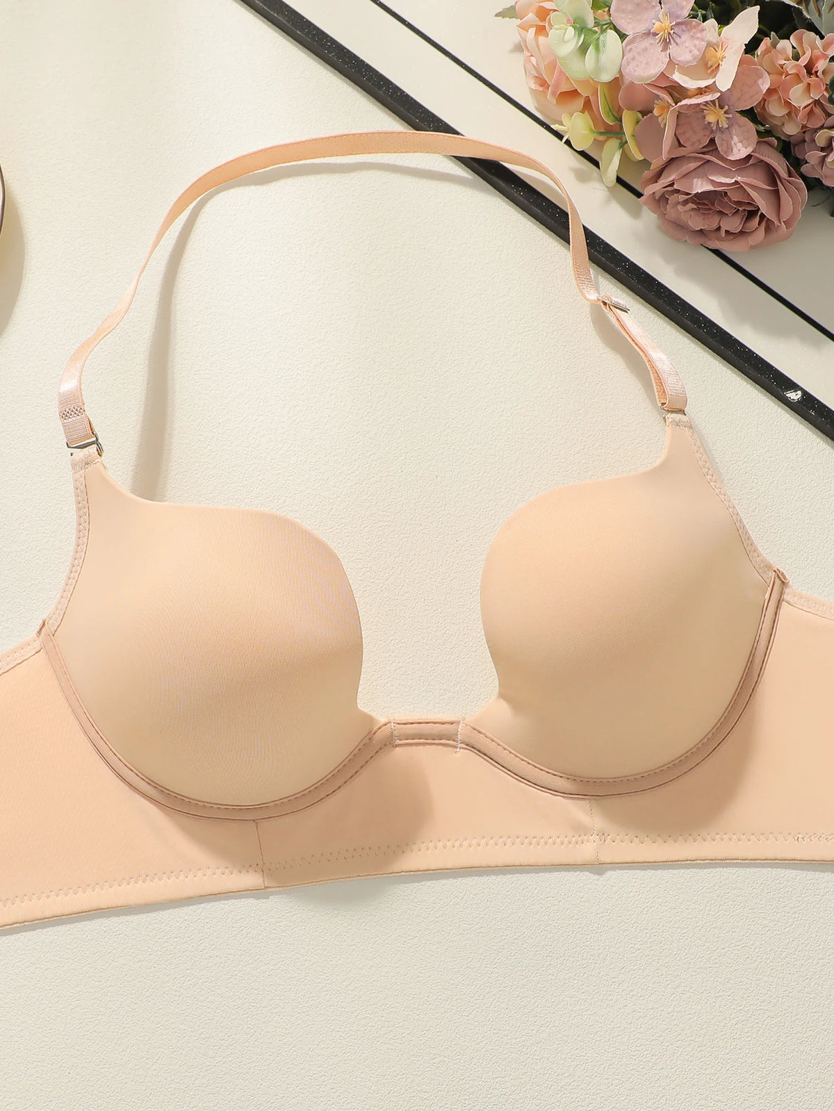 Beige bra on a light background with flowers in the corner