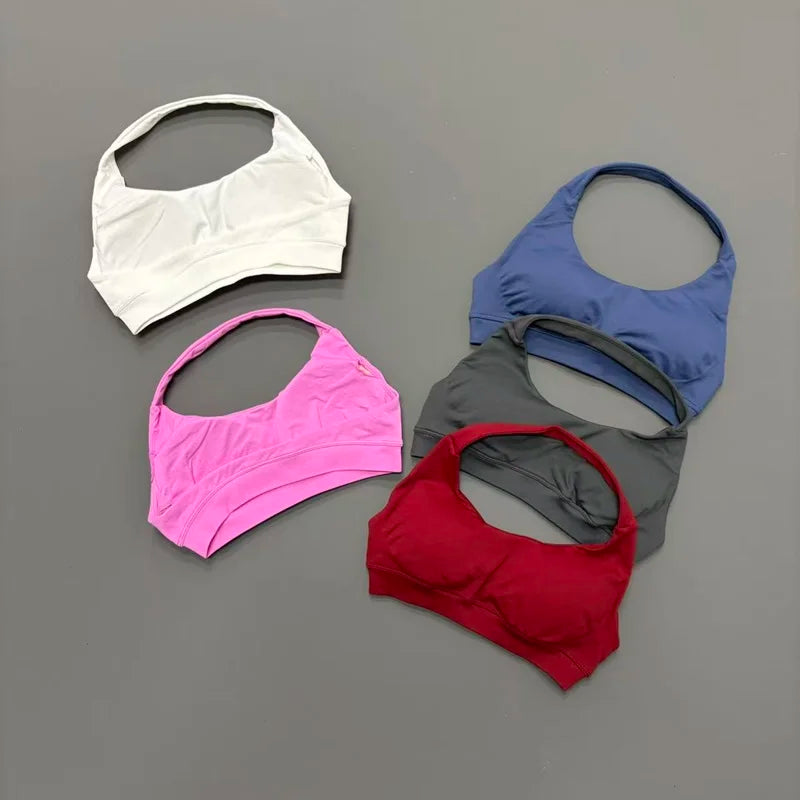 Five sports bras in white, pink, blue, gray, and red on a gray background