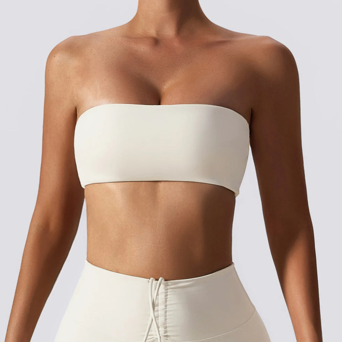 Person wearing a white strapless top and pants on a light gray background