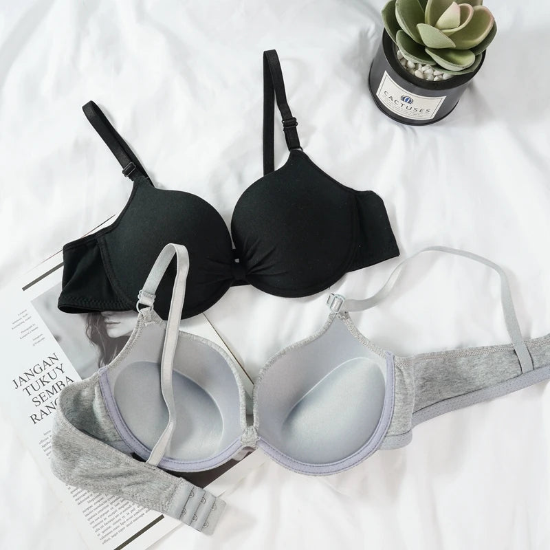 Black and gray bras on a white surface with a plant in the background