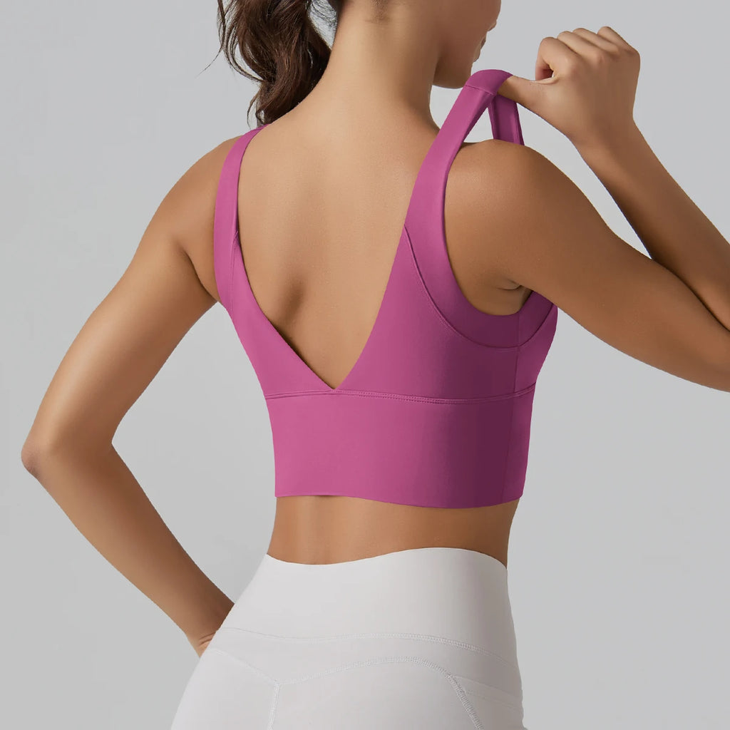 Person wearing a pink sports bra and white pants on a gray background