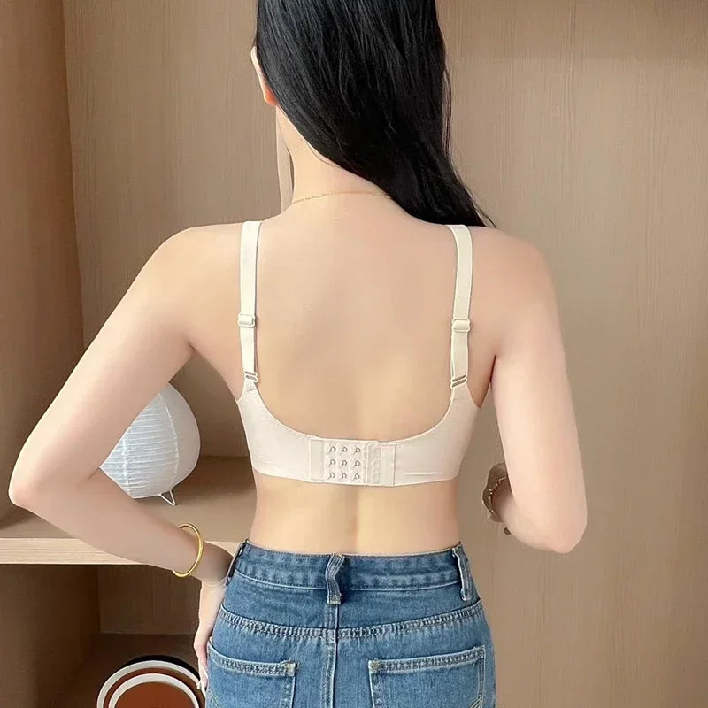 Person wearing a white bra and blue jeans in a neutral setting