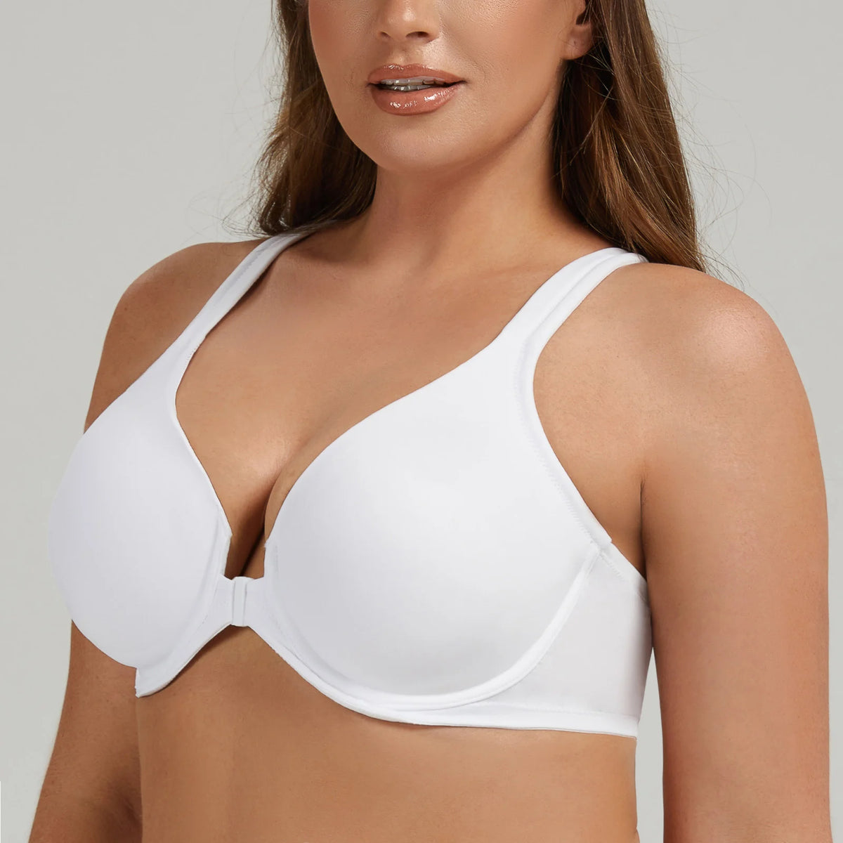 Woman wearing a white bra against a plain background