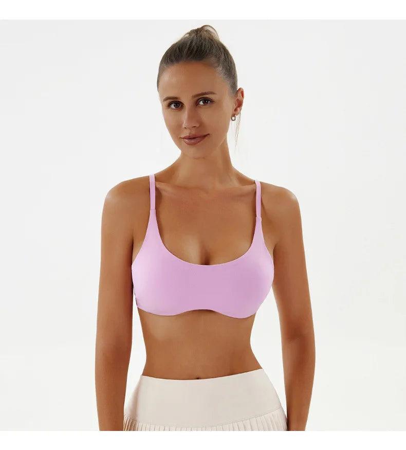 Woman wearing a pink sports bra and white pants on a white background