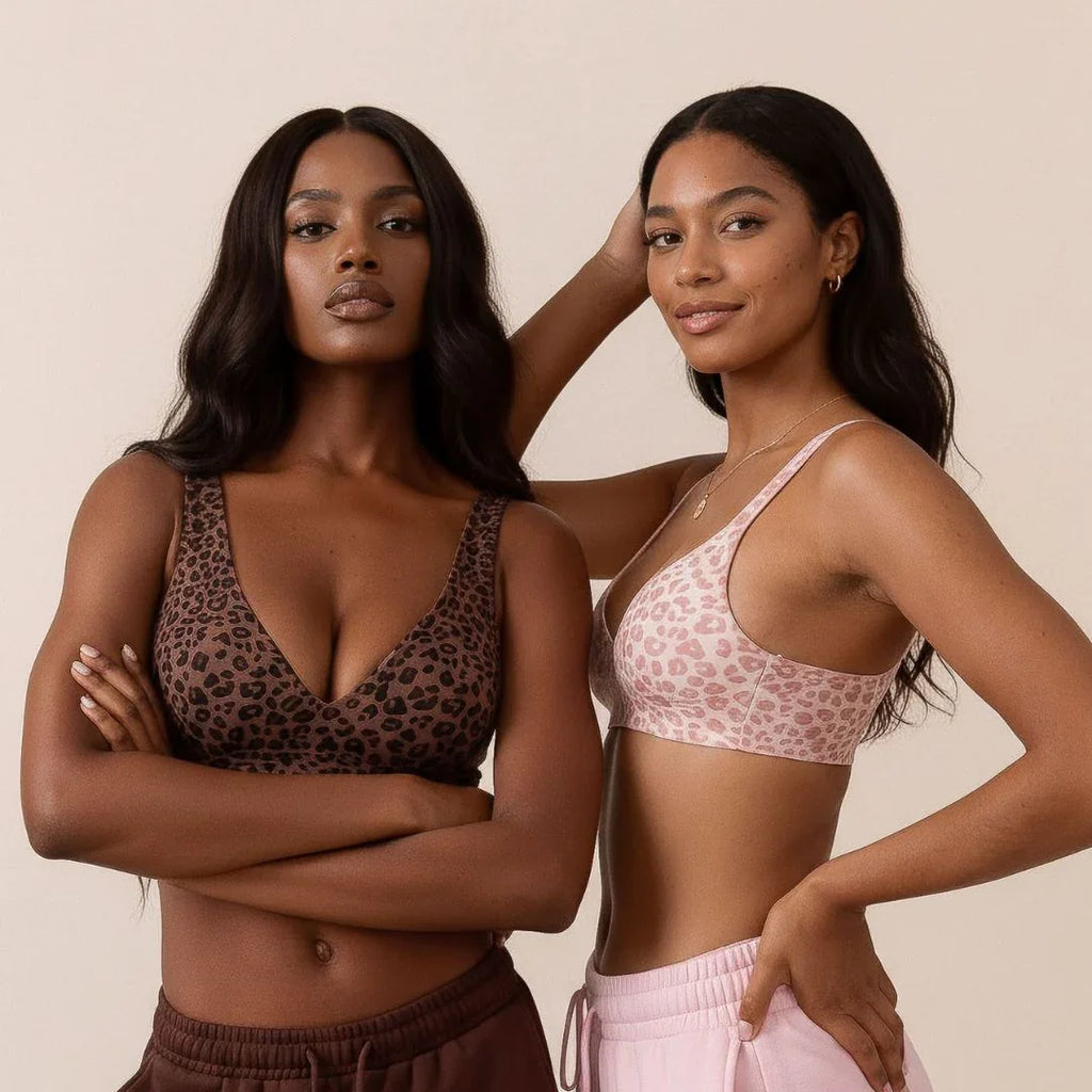 Two women wearing leopard print and pink sports bras with matching pants on a beige background