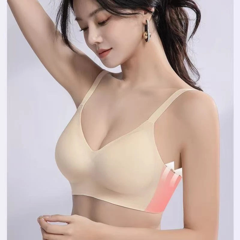 A woman wearing a light beige wireless bra, shown from the chest up against a soft light gray studio background. A pink and white graphic overlay highlights the underwire area of the bra cup.