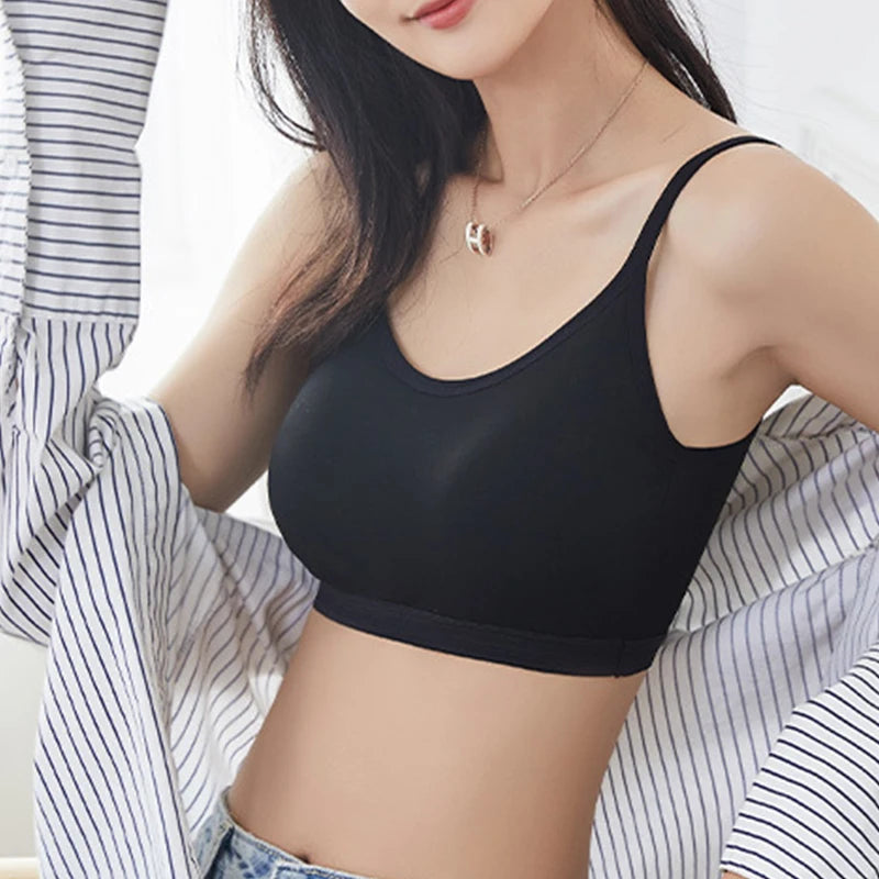 A woman wearing a black wireless scoop-neck bralette, styled with an open striped button-down shirt and a delicate gold necklace.