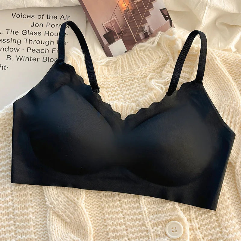 Black wireless bra with scalloped cups, laid flat on a cream knit sweater with a magazine in the background.