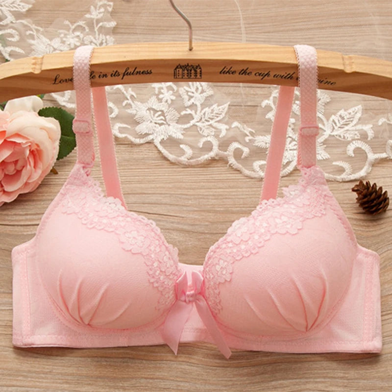Pink bra on a wooden hanger with floral background