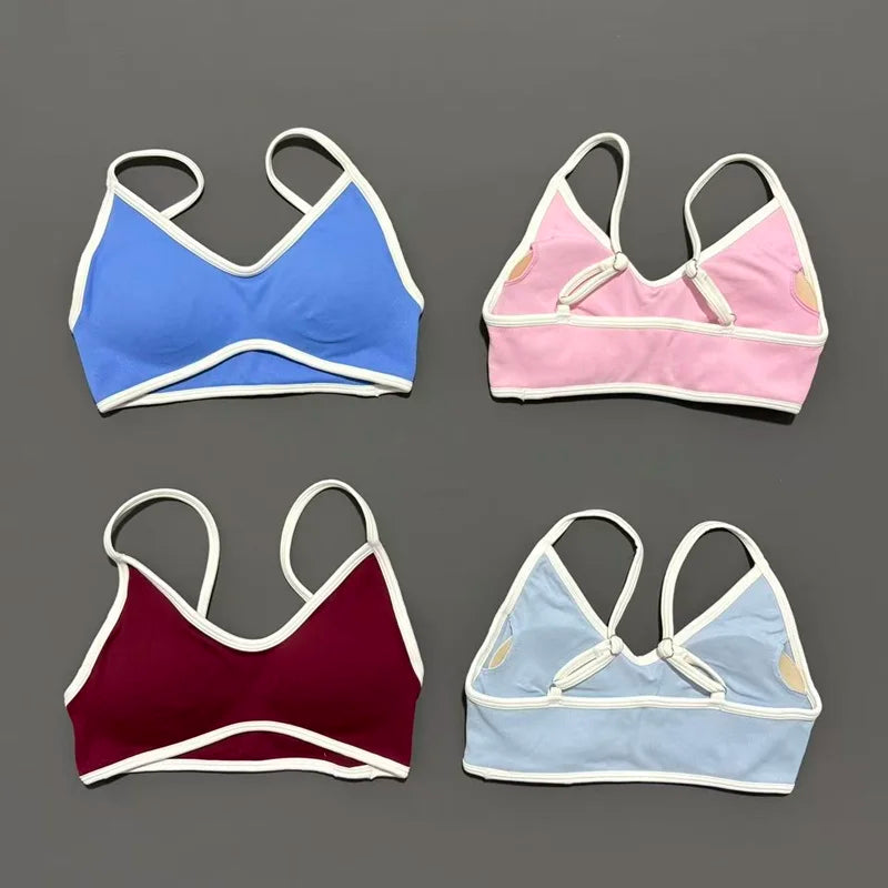 Four sports bras in blue, pink, red, and light blue on a gray background