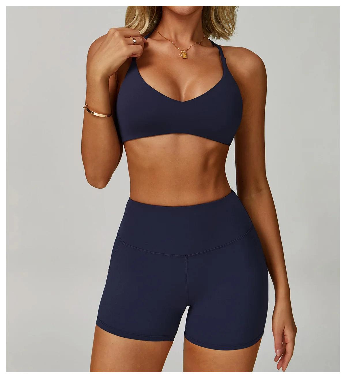 Woman wearing a navy blue sports bra and shorts set on a plain background
