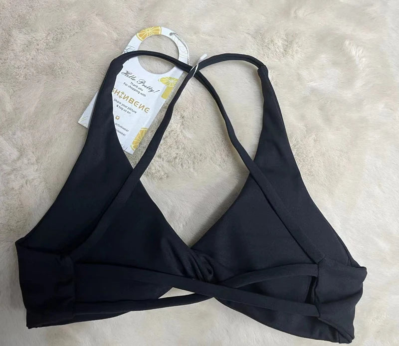 Black bikini top on a beige surface with a tag attached