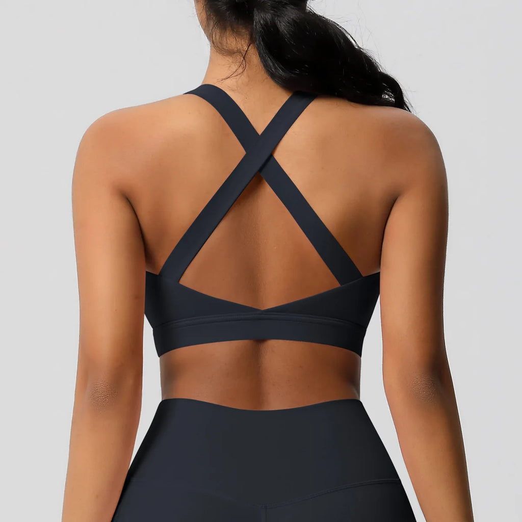 Black sports bra with criss-cross design on a plain background