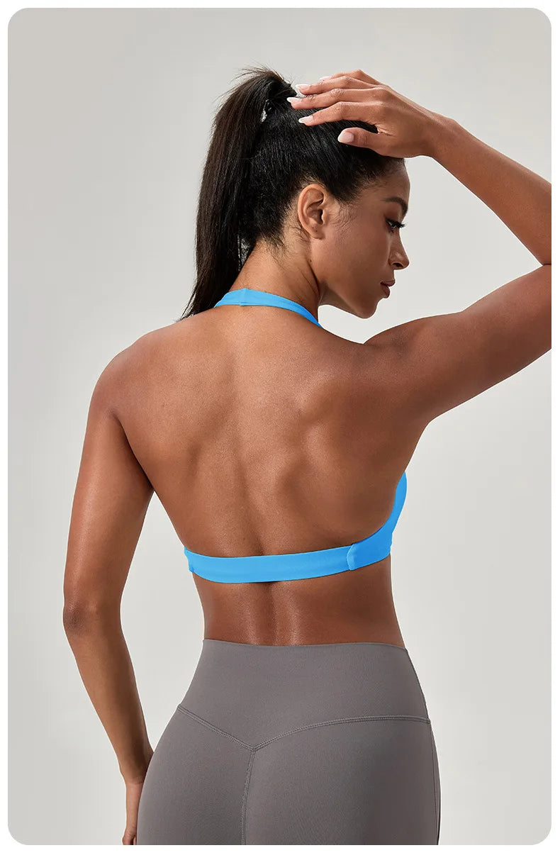 Woman wearing a blue sports bra and gray leggings against a light gray background