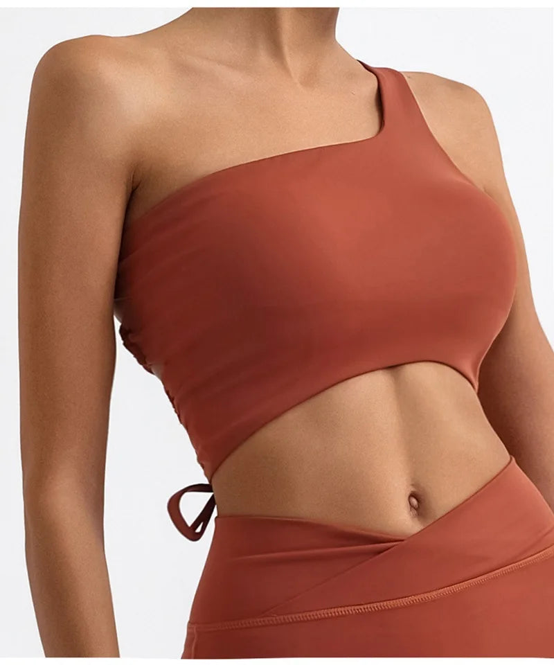 Brown one-shoulder top worn by a person on a white background