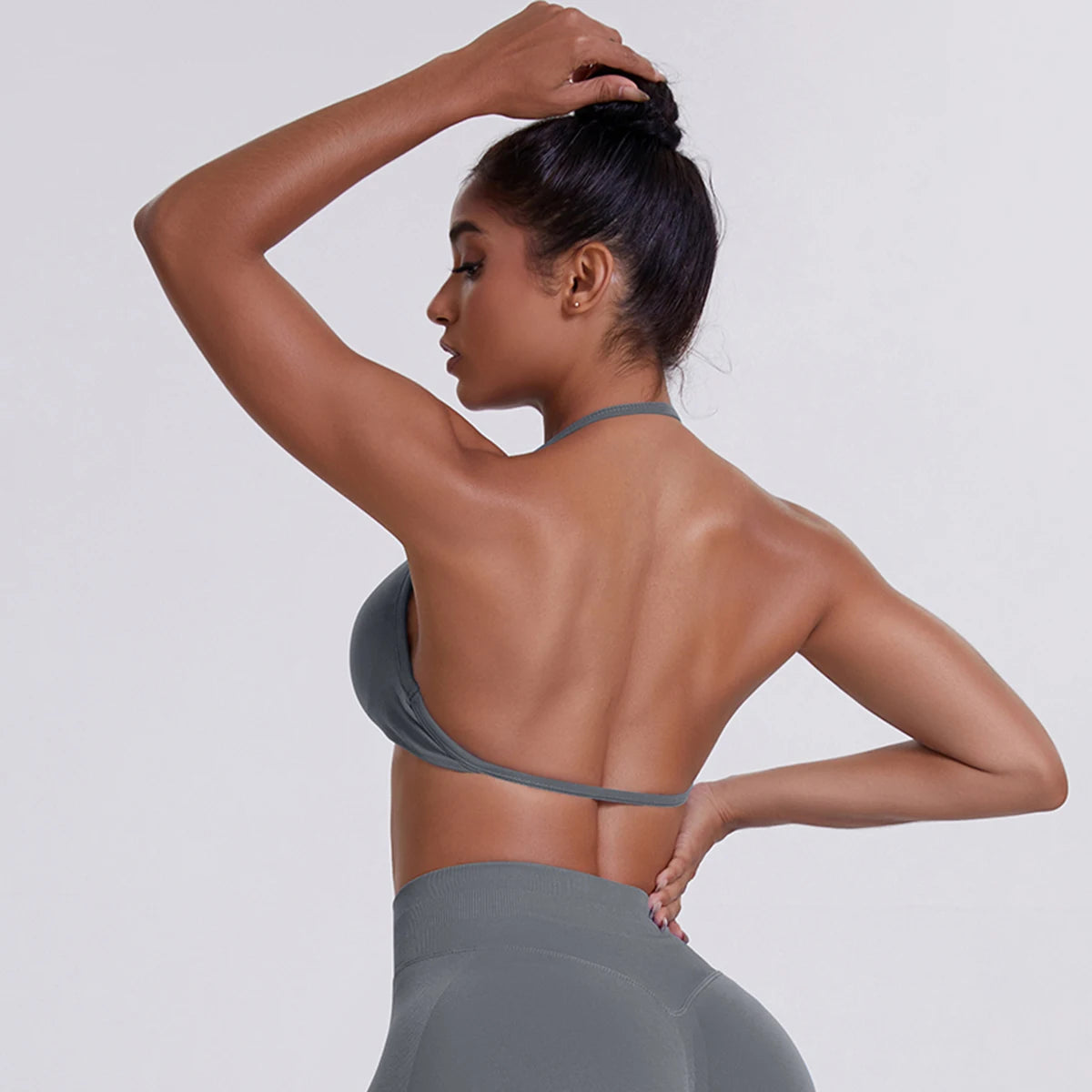 Woman wearing a gray halter top and high-waisted leggings against a white background