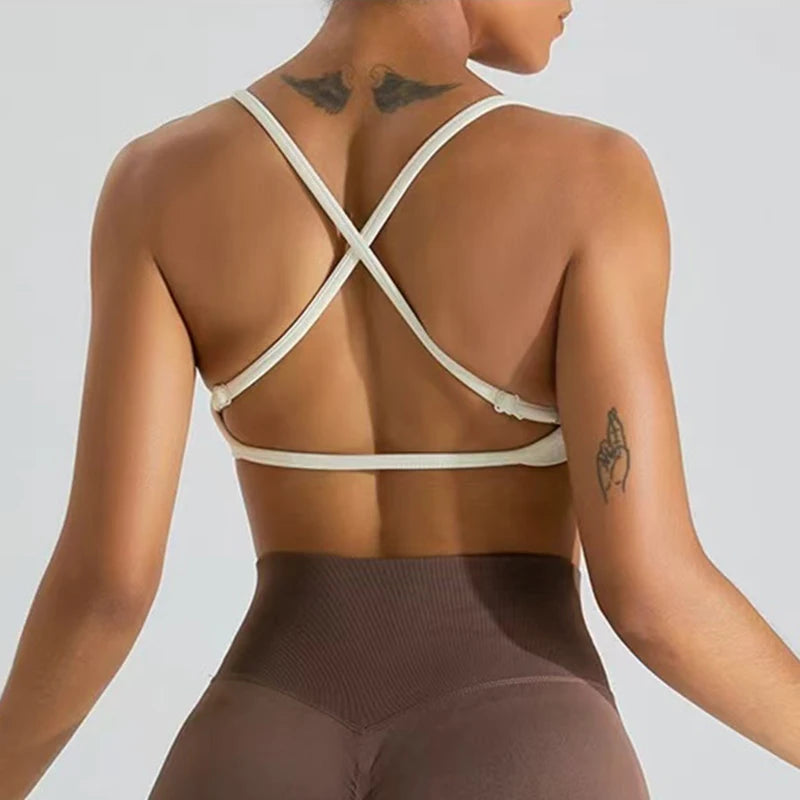 Person wearing a beige sports bra and brown leggings on a plain background