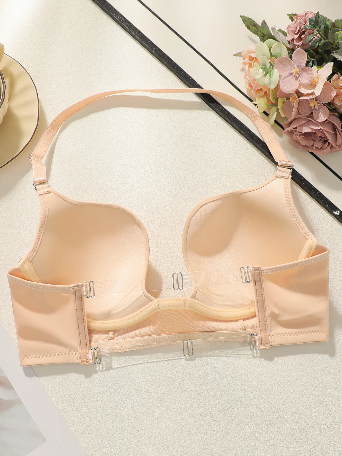 Beige bra on a white surface with flowers in the background