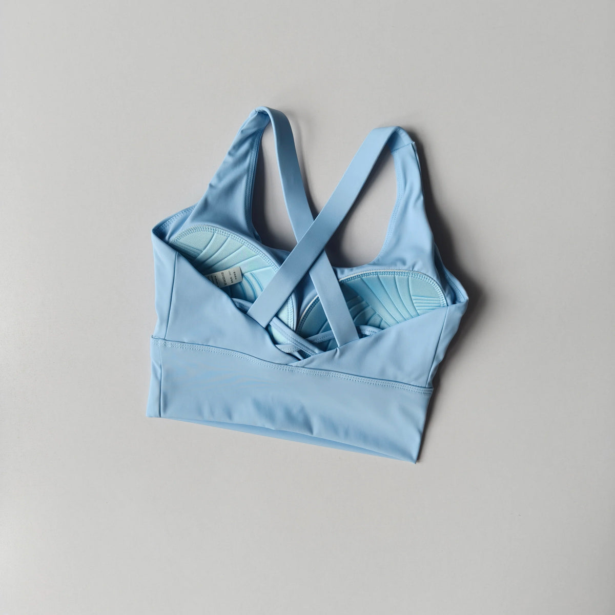 Light blue sports bra with criss-cross straps on a gray background