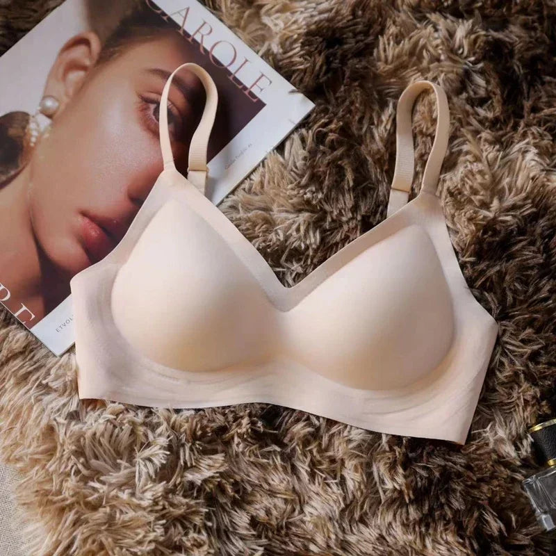 Beige bra on a textured surface with a magazine and perfume bottle in the background