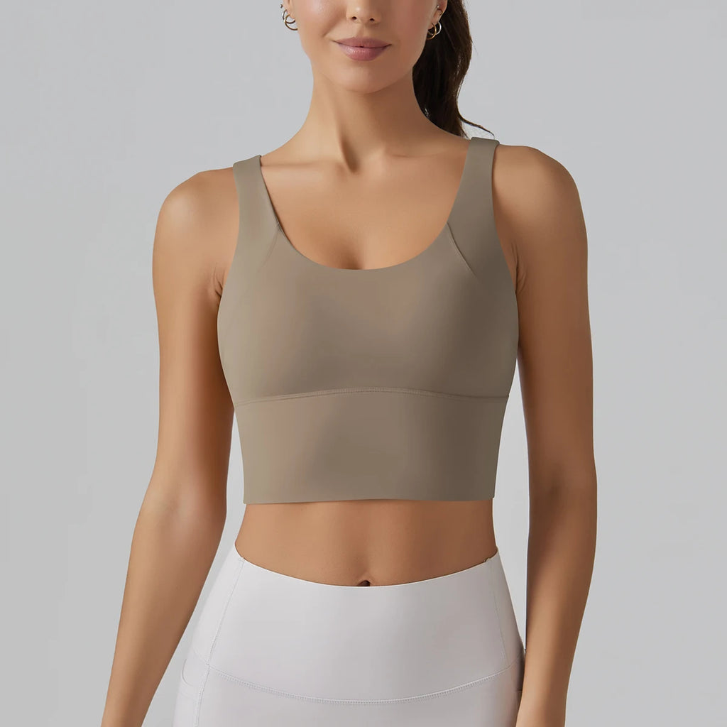 Woman wearing a beige sports bra and white pants on a gray background