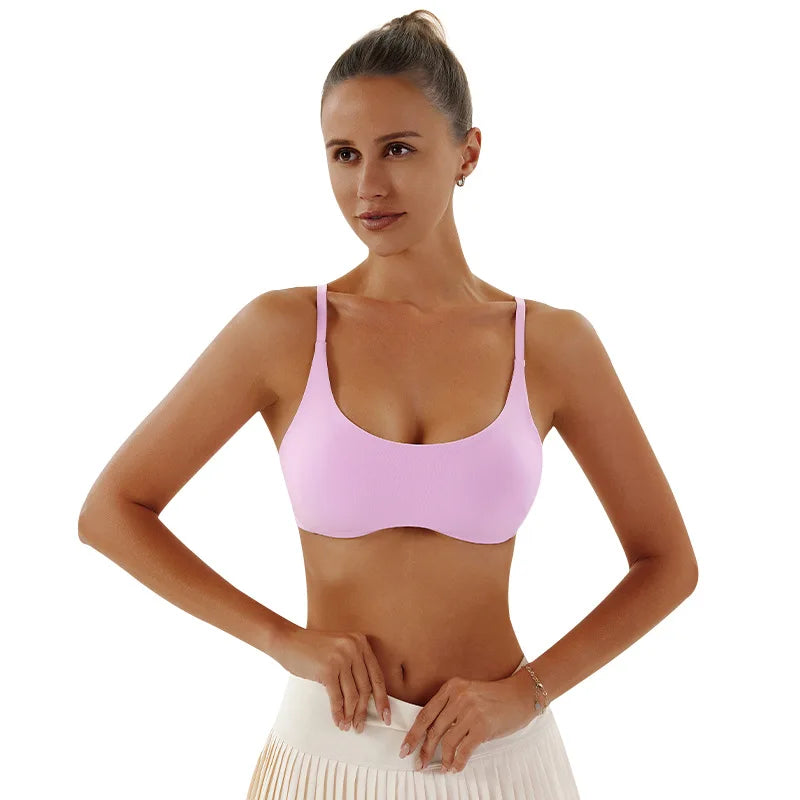 Woman wearing a pink sports bra and white pants on a white background