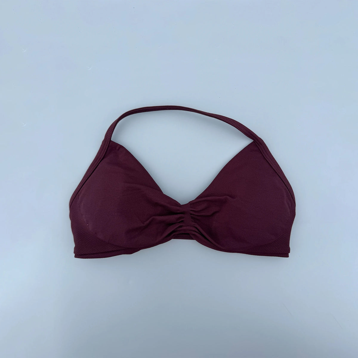 Maroon bikini top on a light blue background