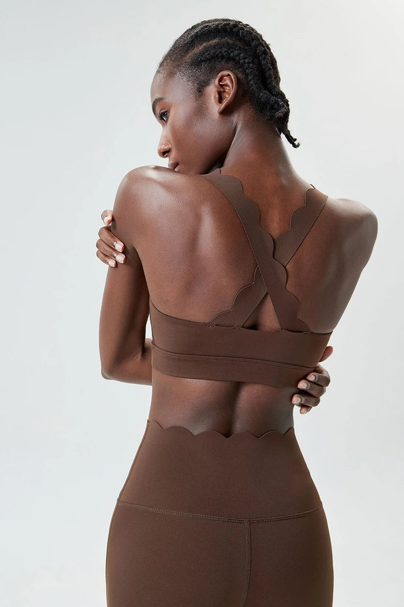 Woman wearing a brown sports bra and leggings against a light gray background