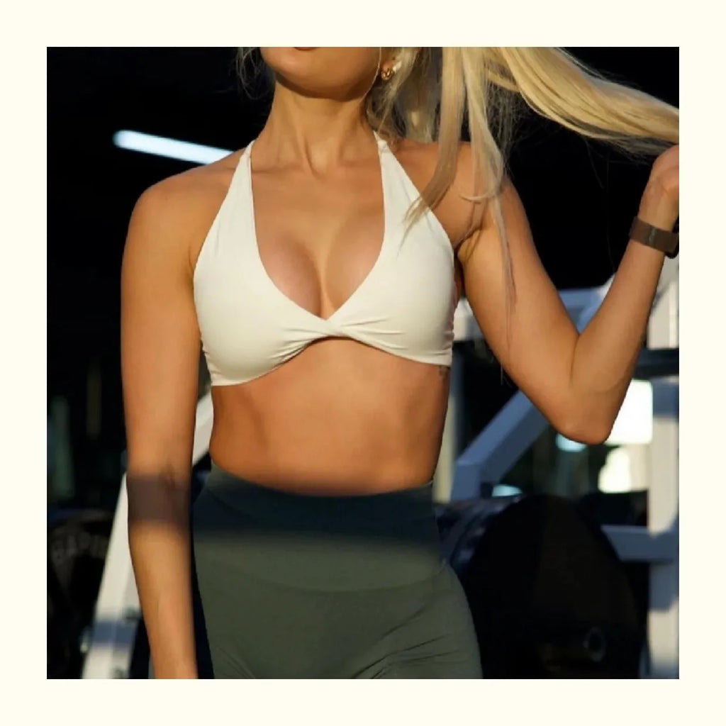 Woman wearing a beige sports bra and green leggings against a blurred background