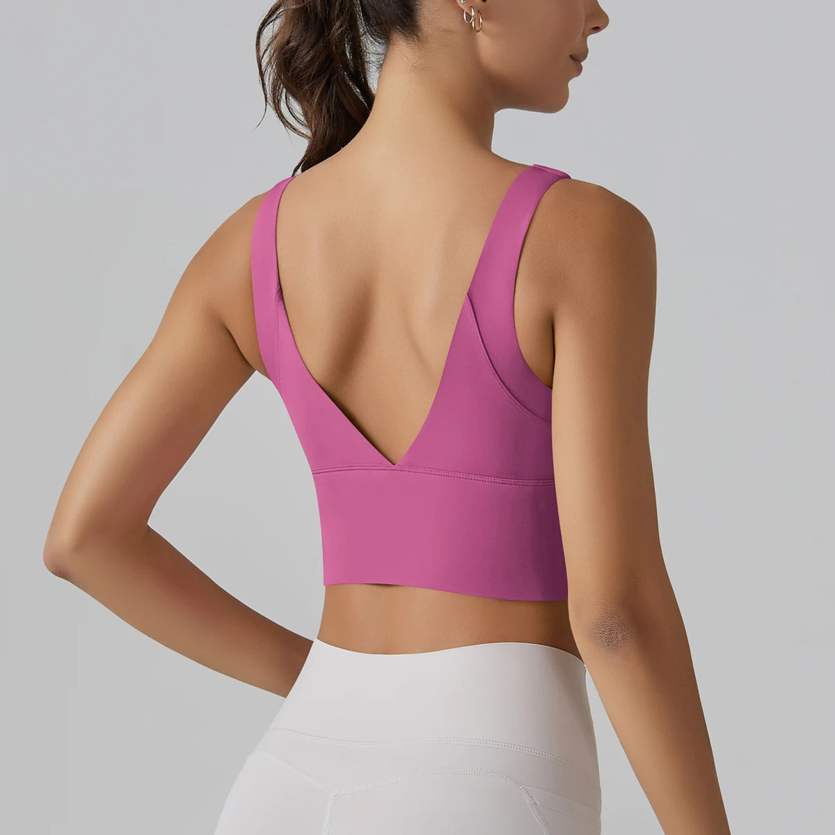 Person wearing a pink sports bra and white leggings on a gray background