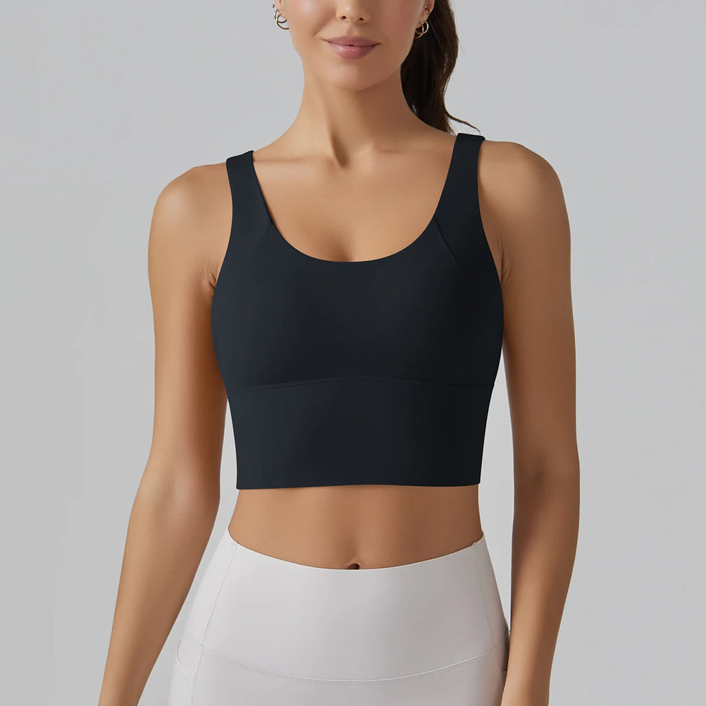 Woman wearing a black sports bra and white pants on a gray background