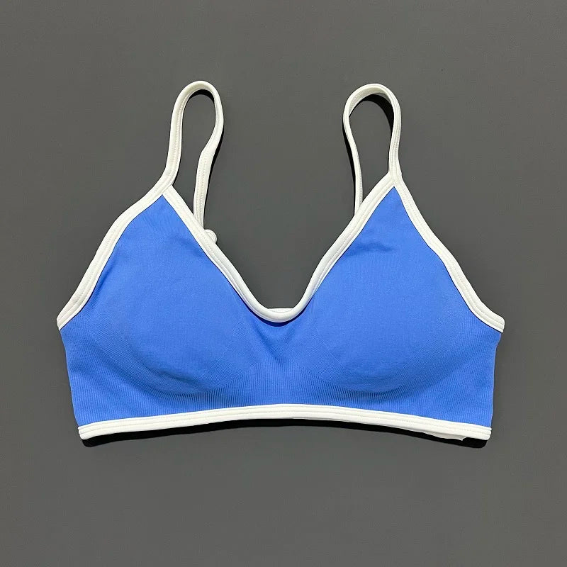 Blue sports bra with white trim on a gray background