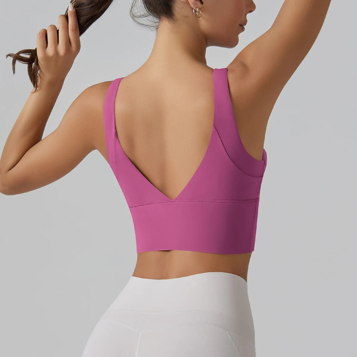 Person wearing a pink sports bra and white leggings on a gray background