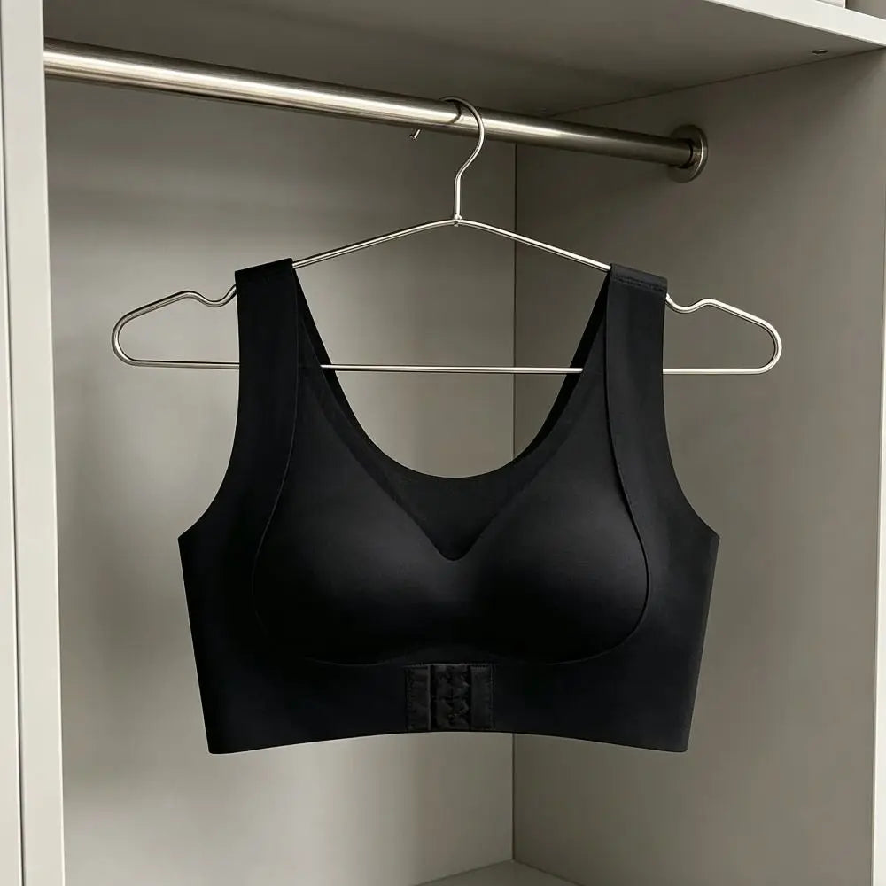 A black wireless bralette hanging on a silver metal hanger inside an open closet with a white shelf and silver rod.