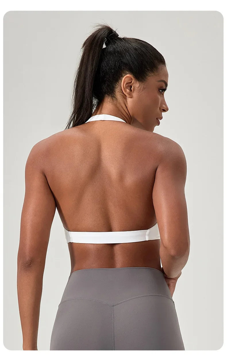 Woman wearing a white sports bra and gray leggings on a light gray background