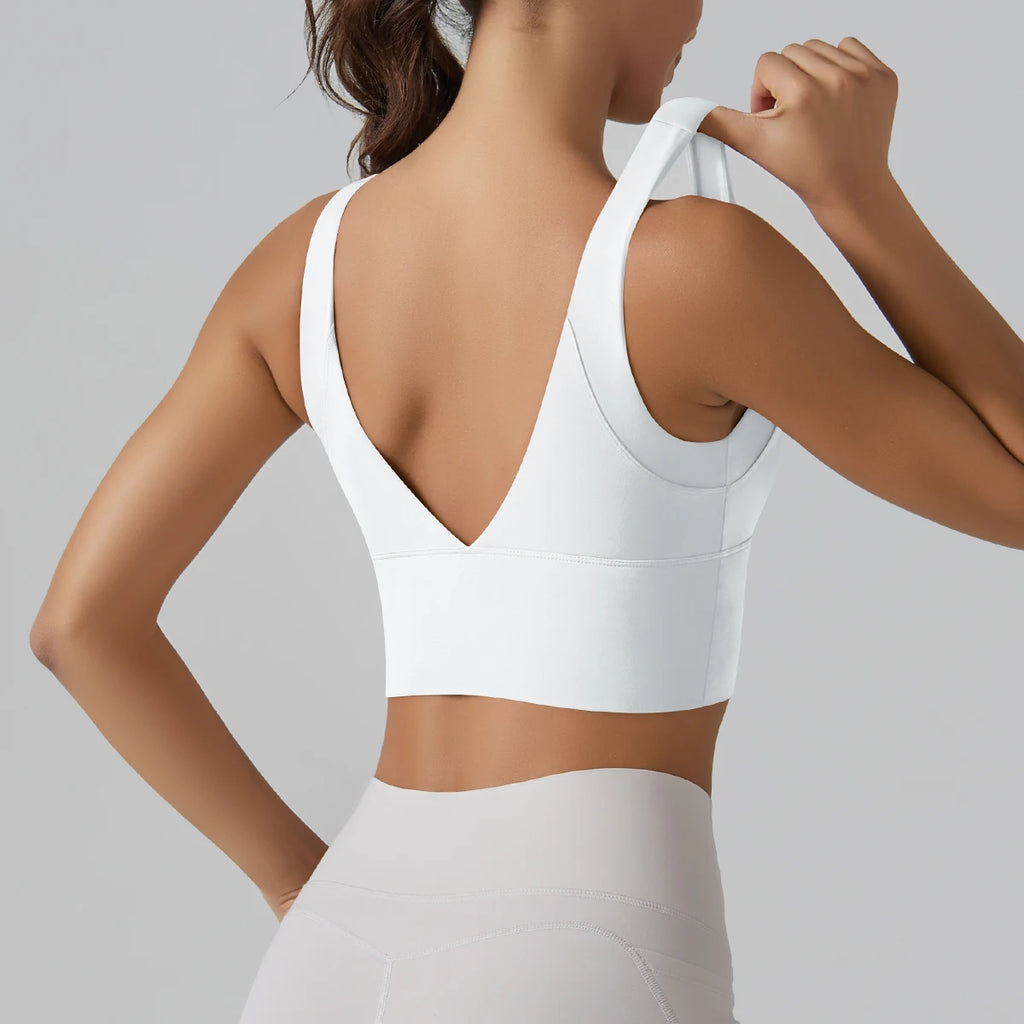 Person wearing a white sports bra and leggings on a gray background