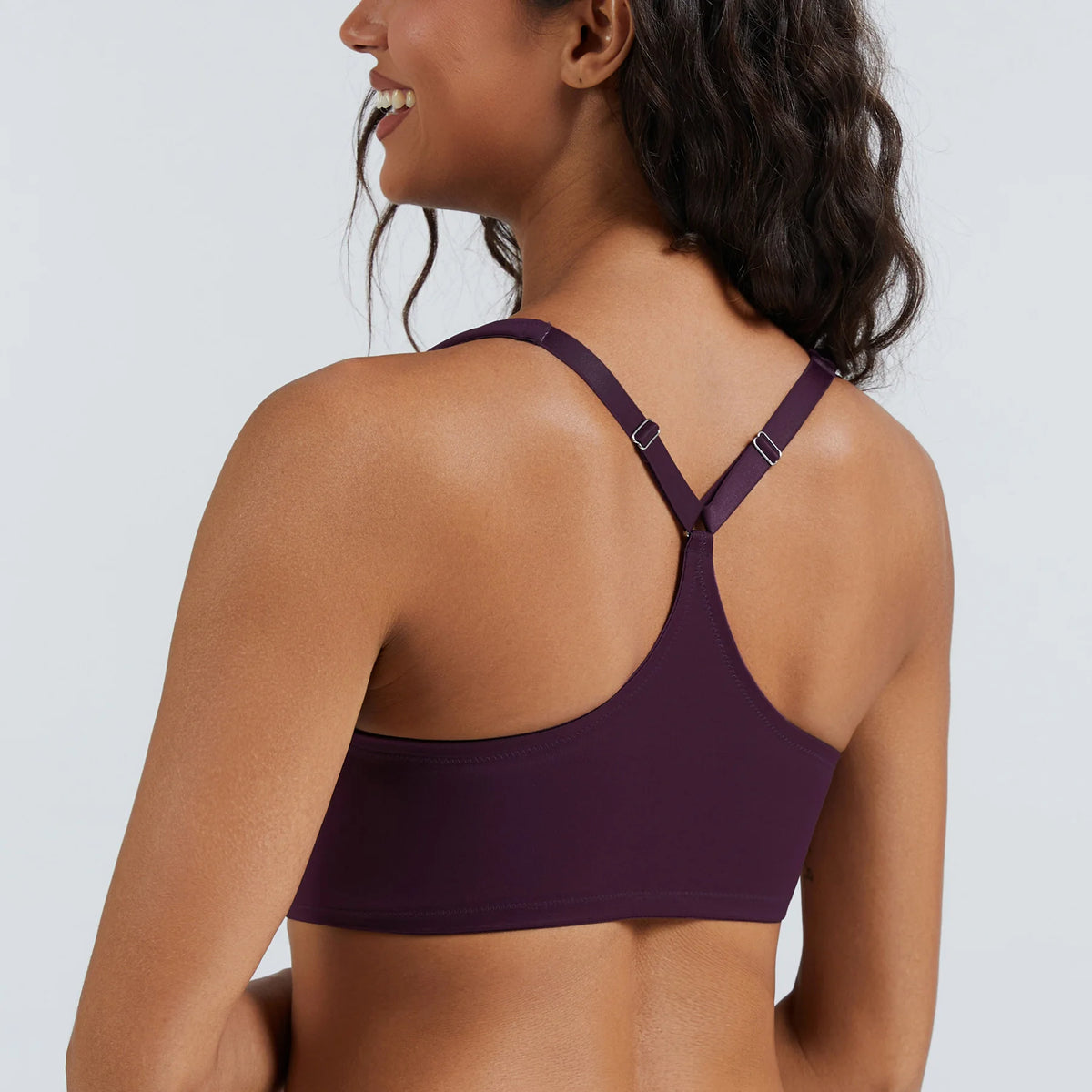 Woman wearing a purple sports bra against a plain background