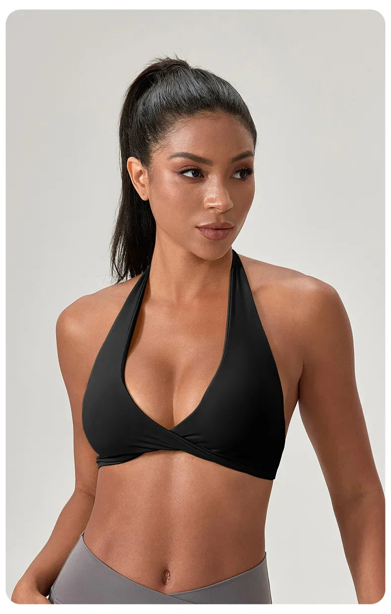 Woman wearing a black sports bra and gray leggings on a plain background