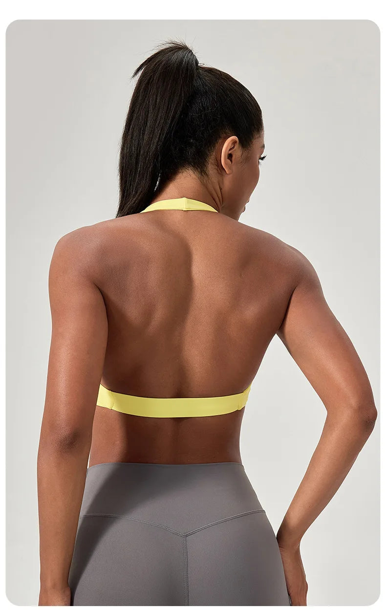 Woman wearing a yellow sports bra and gray leggings on a light gray background