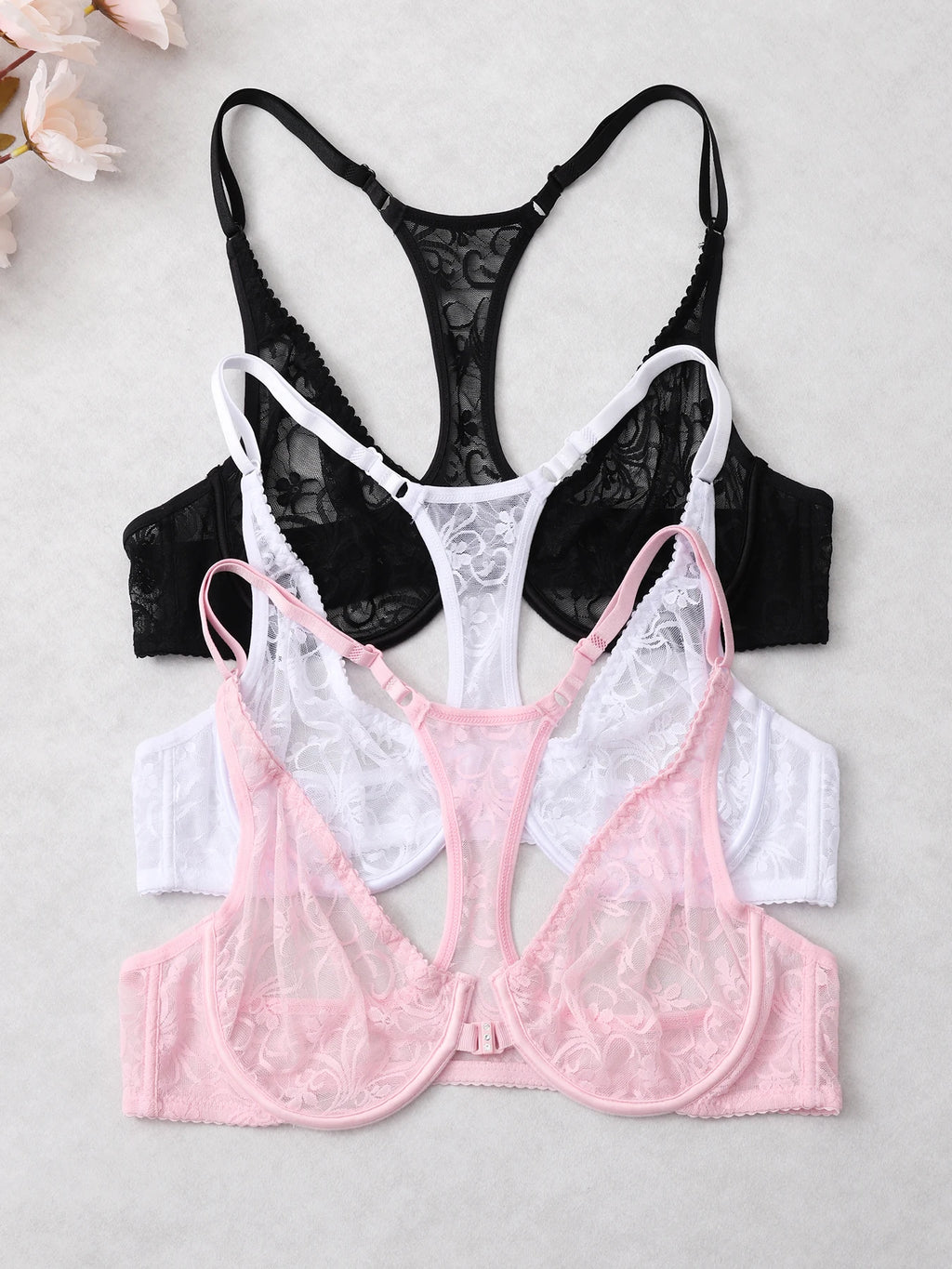 Three lace bras in black, white, and pink on a light gray background.