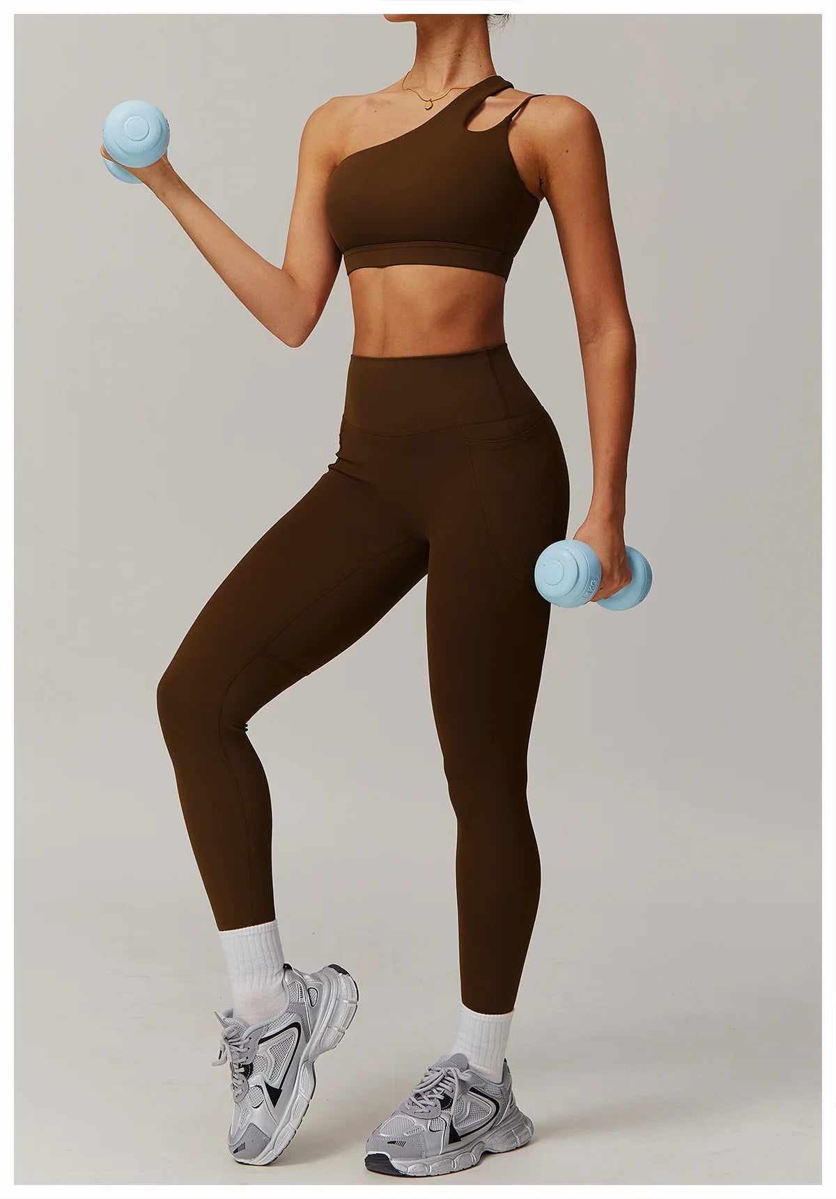 Person wearing a brown athletic outfit with blue dumbbells on a plain background