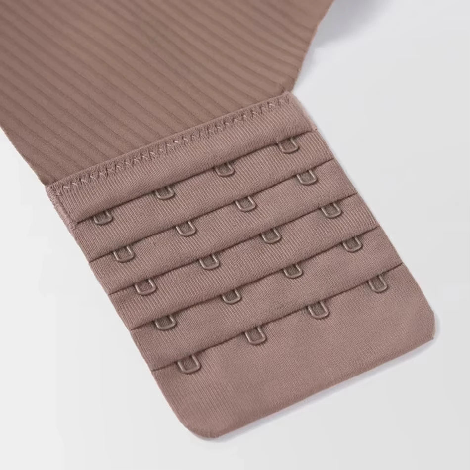 Close-up of beige bra strap with multiple hooks on a light gray background