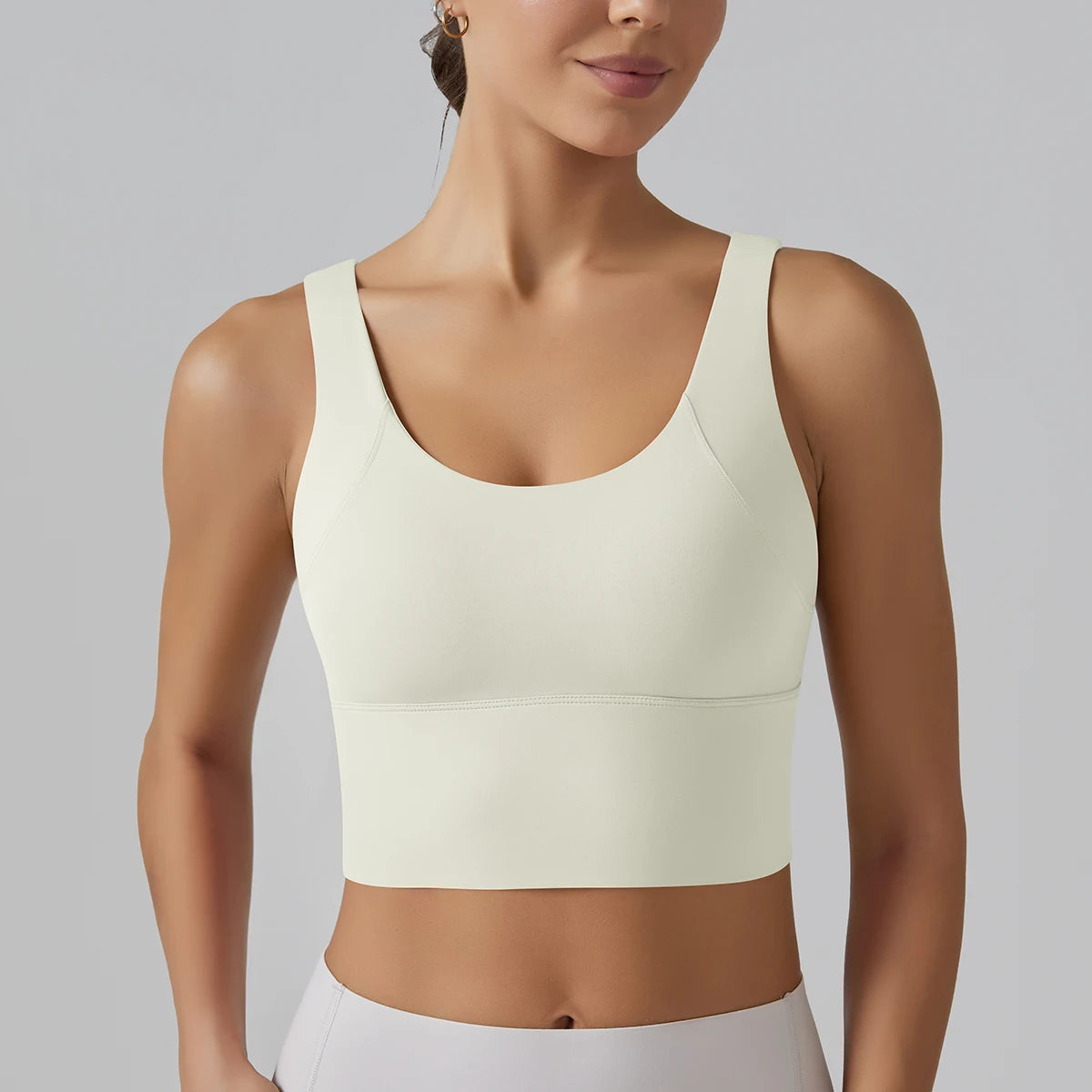 Woman wearing a light-colored sports bra against a gray background