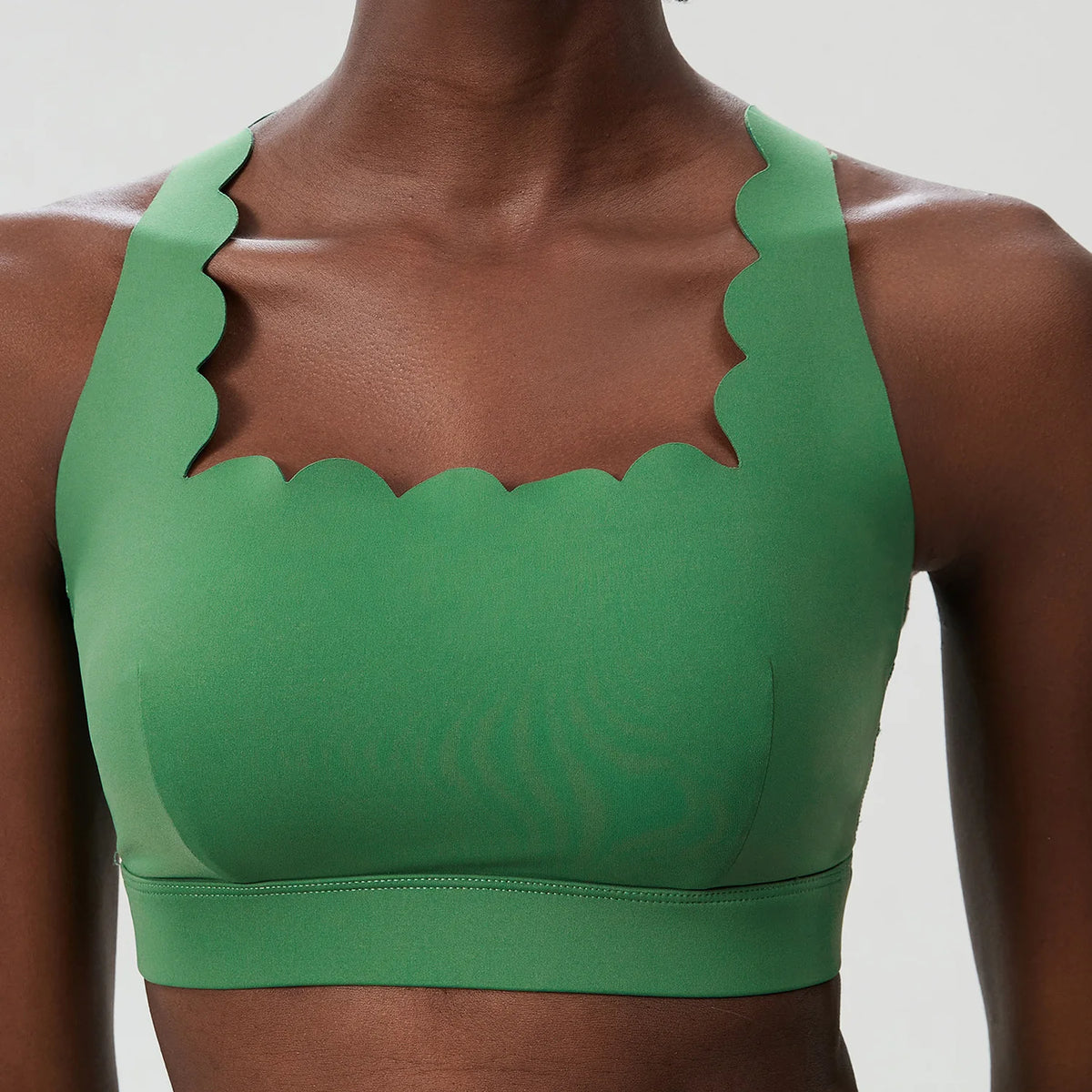 Green sports bra with scalloped edges on a neutral background