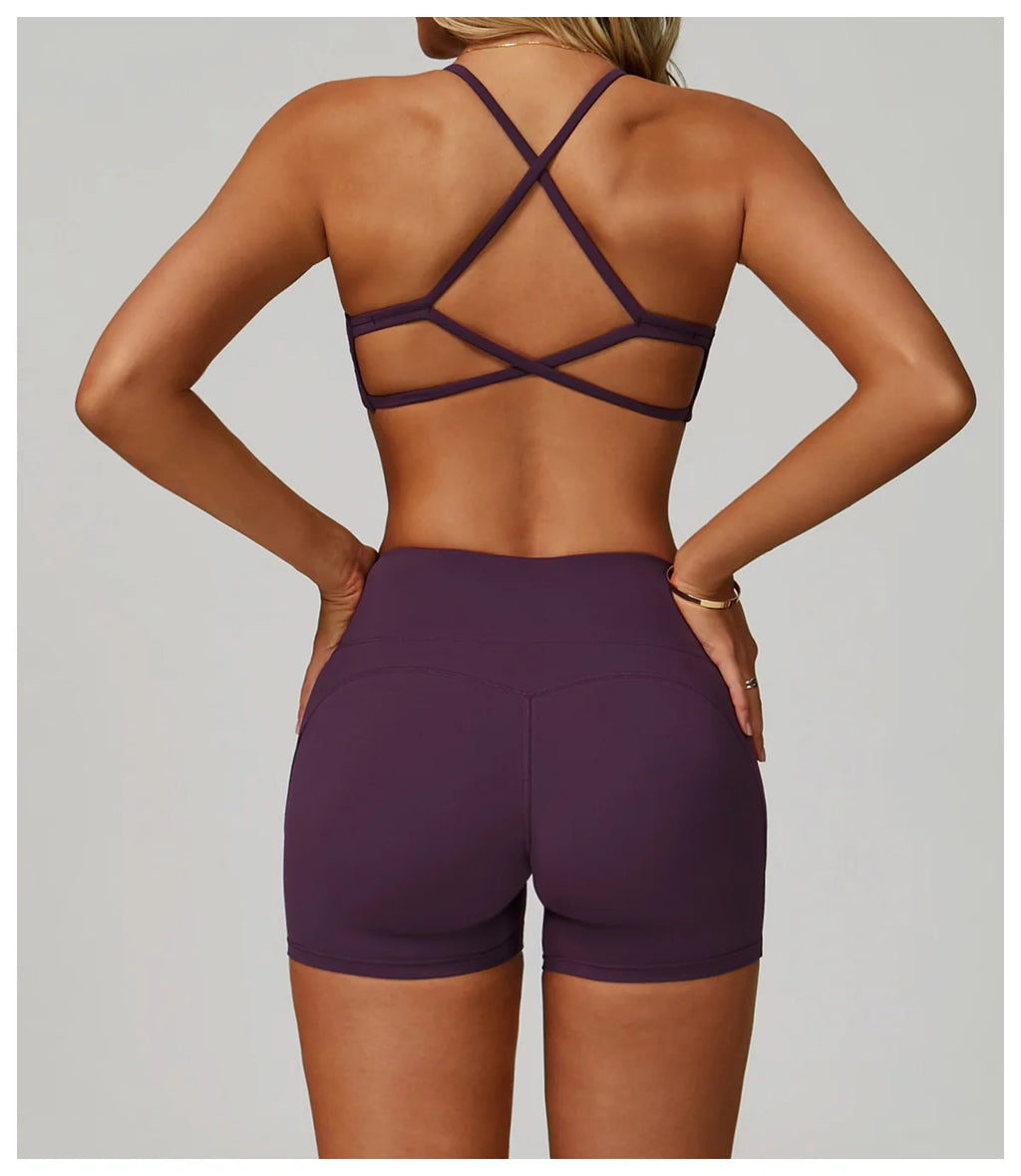 Person wearing a purple sports bra and shorts set on a plain background