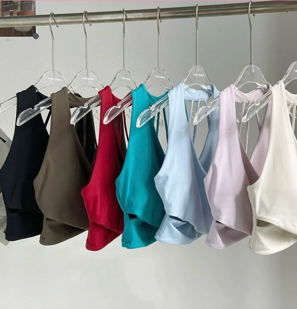 Row of colorful sleeveless tops on hangers against a white background