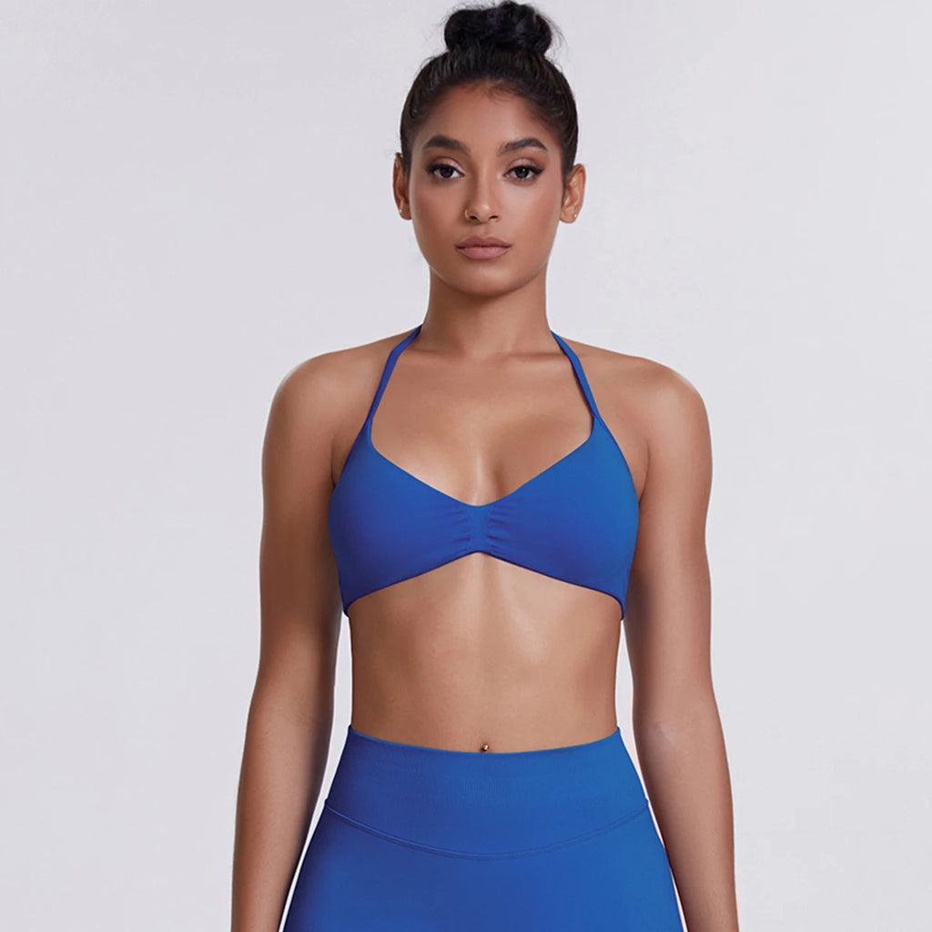 Woman wearing a blue sports bra and leggings on a light gray background