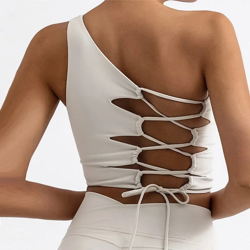 White one-shoulder top with lace-up back design on a plain background